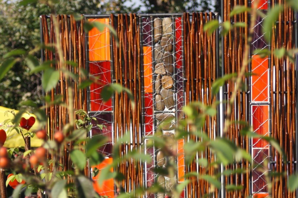 Sichtschutz in rot-orangem Glas in Kombination mit Weide