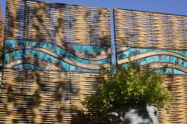 Sichtschutz mit blauen Glaselementen und Weide